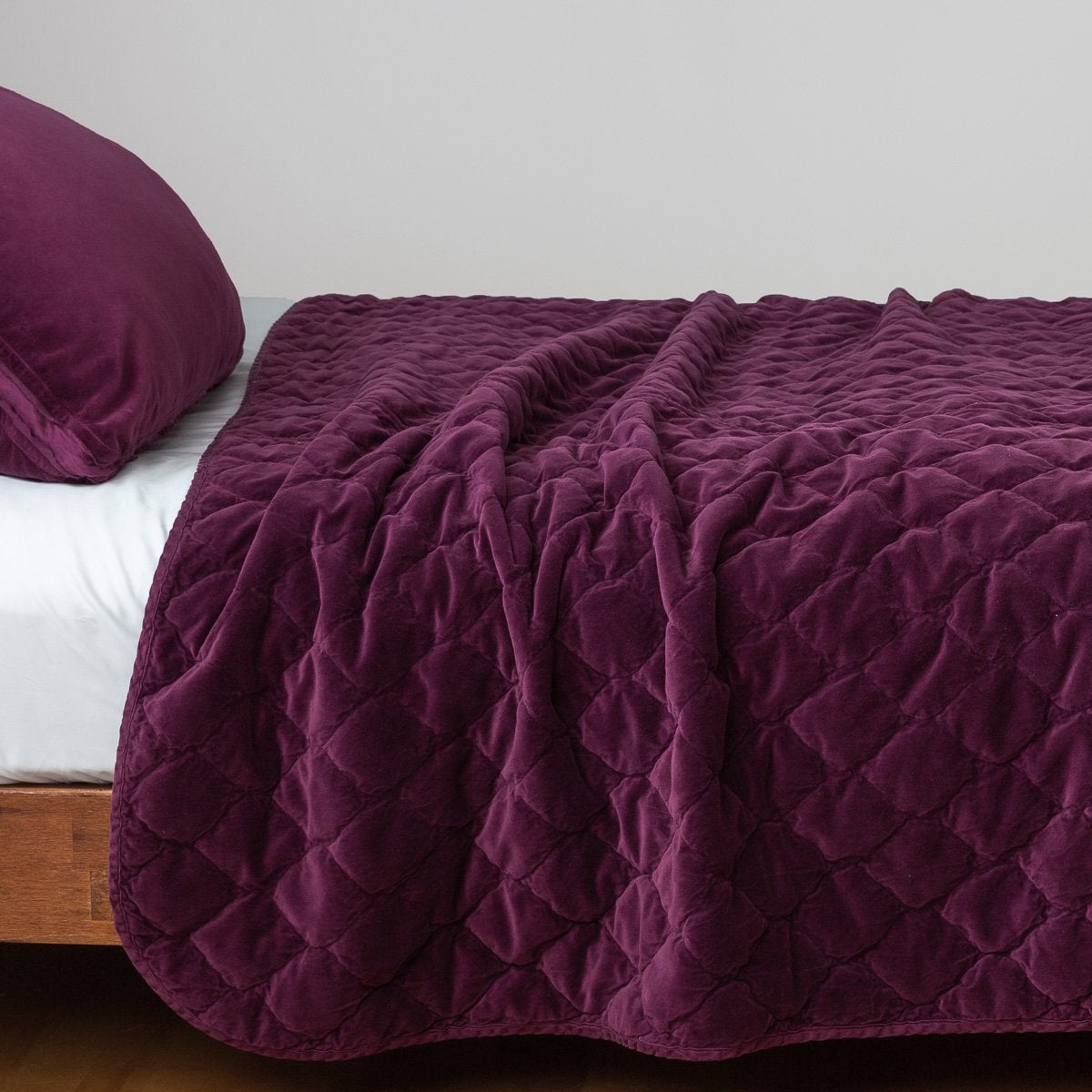 Fig: Quilted cotton velvet coverlet draped over a white fitted sheet - side view.