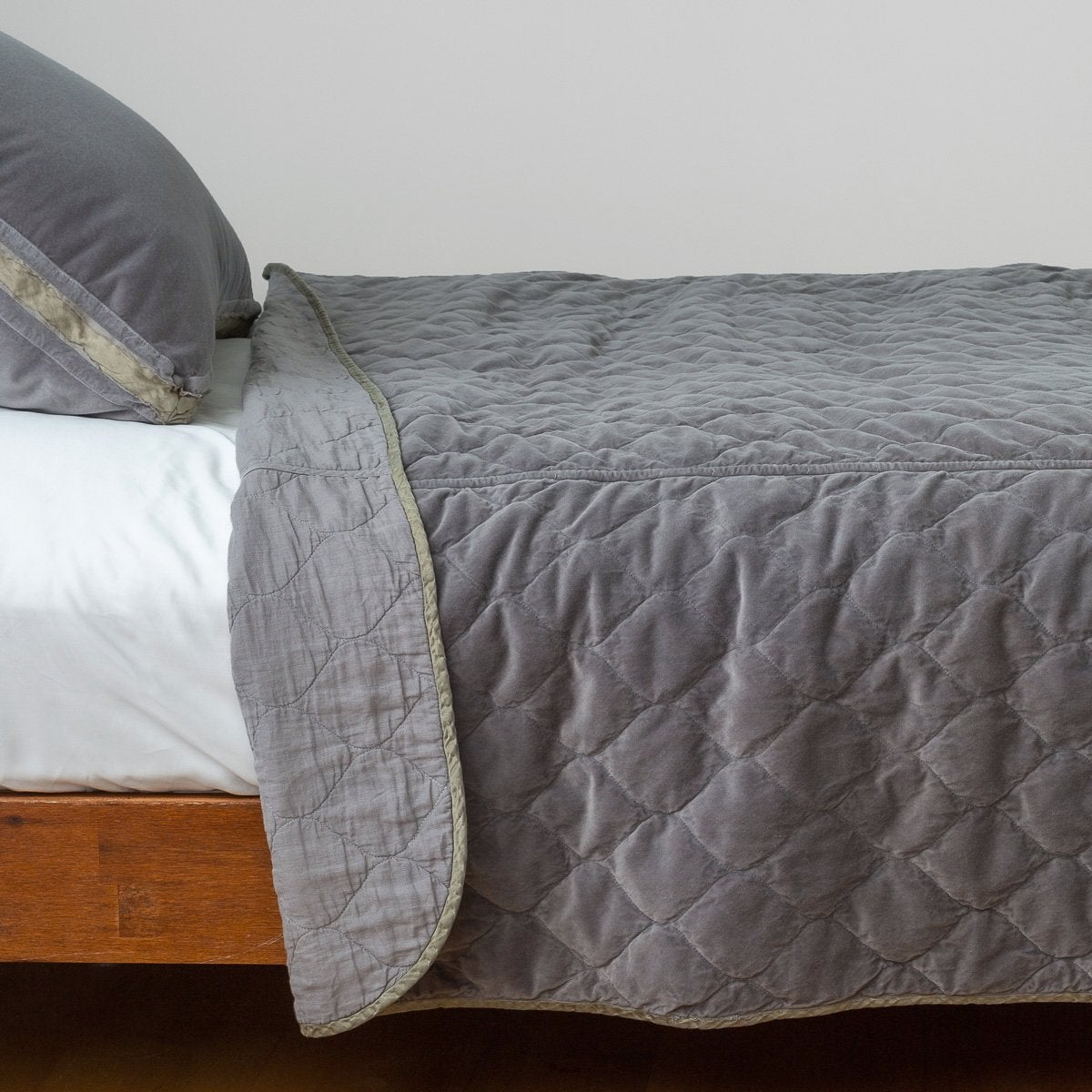 Moonlight: Quilted cotton velvet coverlet, folded back to showcase linen back, draped over white sheeting - side view.