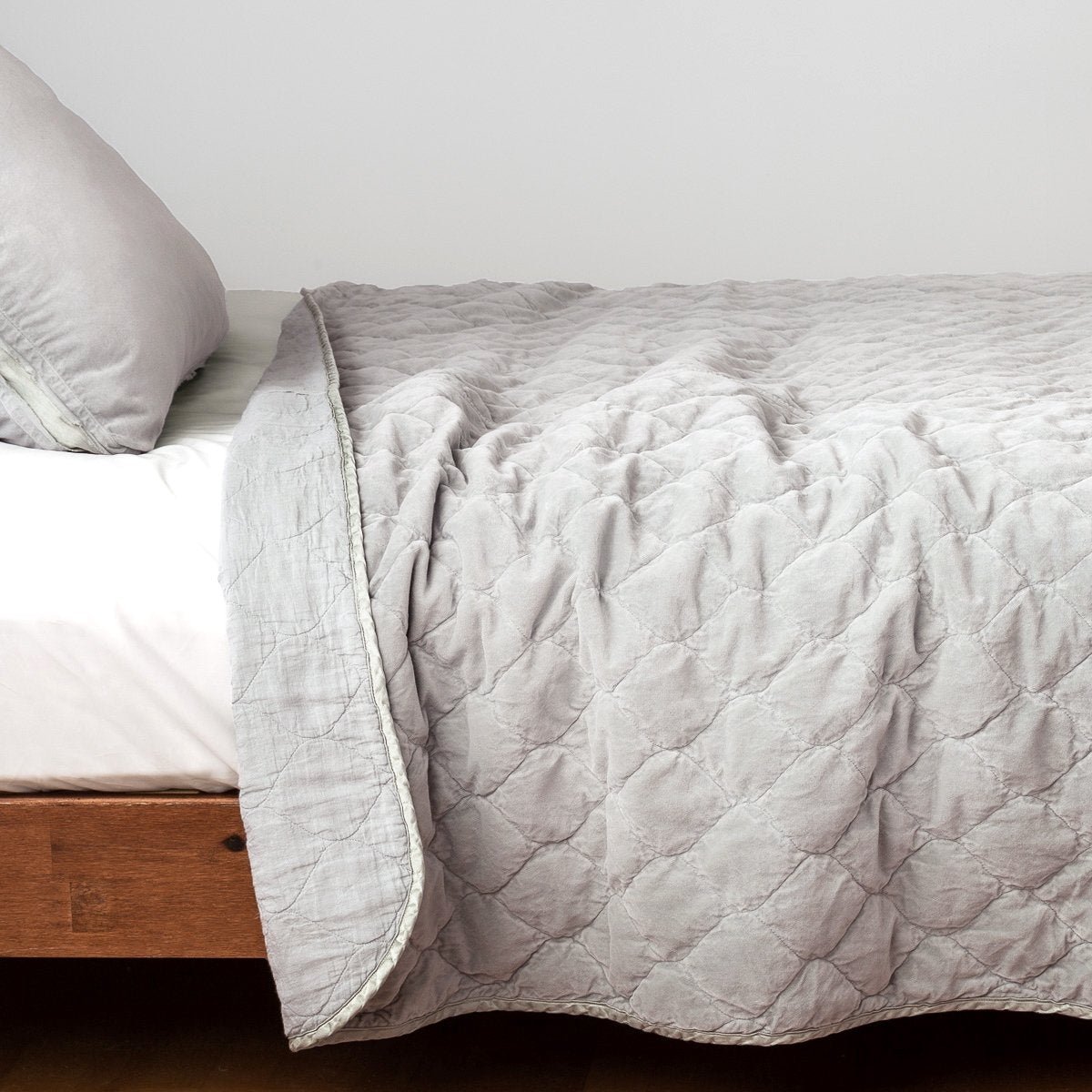 : Harlow coverlet in sterling, with top folded back to showcase linen back, draped over a white fitted sheet - side view.