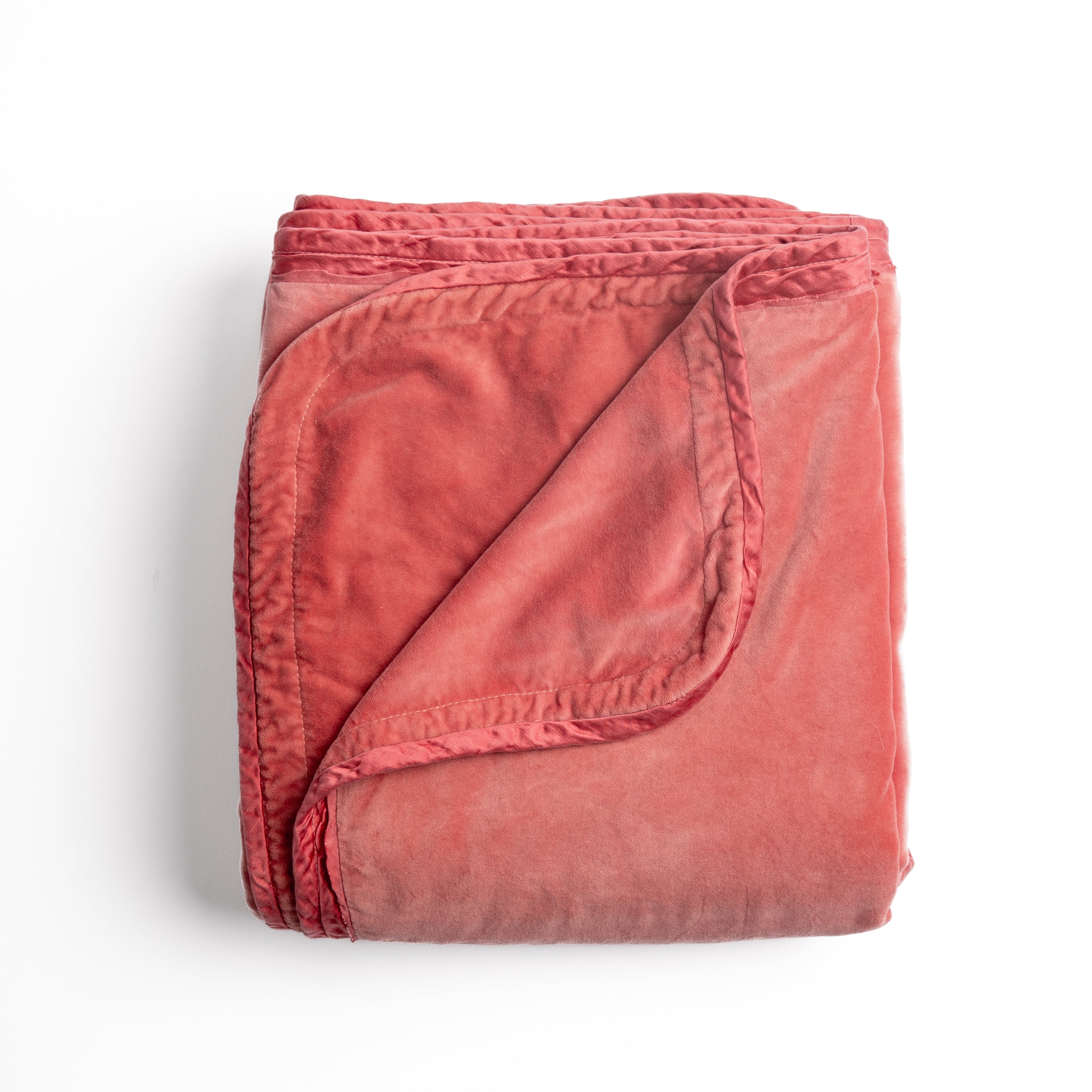 Poppy: overhead angle of the folded blanket with a corner pulled back to show the reverse and trim. 