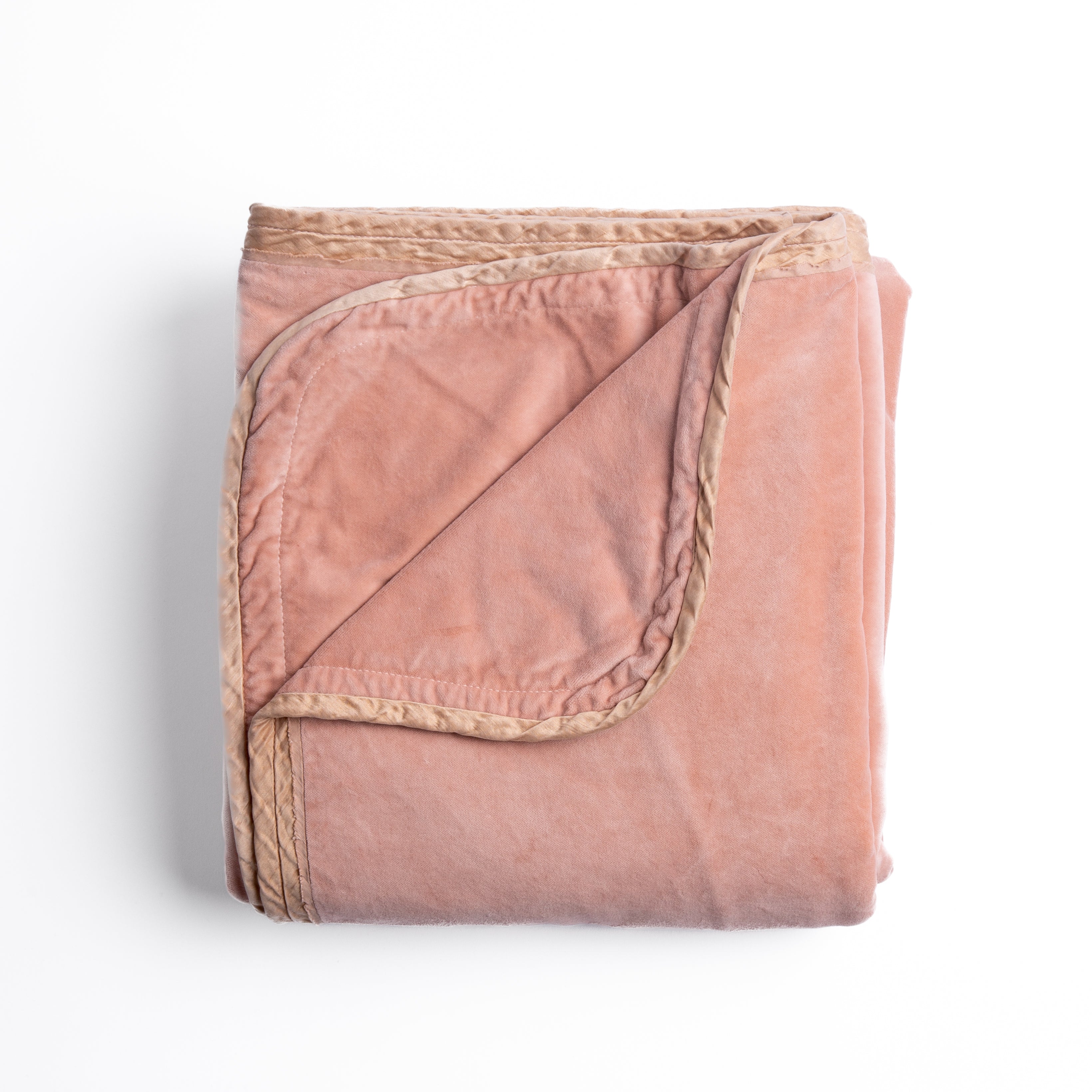 Rouge: overhead angle of the folded blanket with a corner pulled back to show the reverse and trim. 