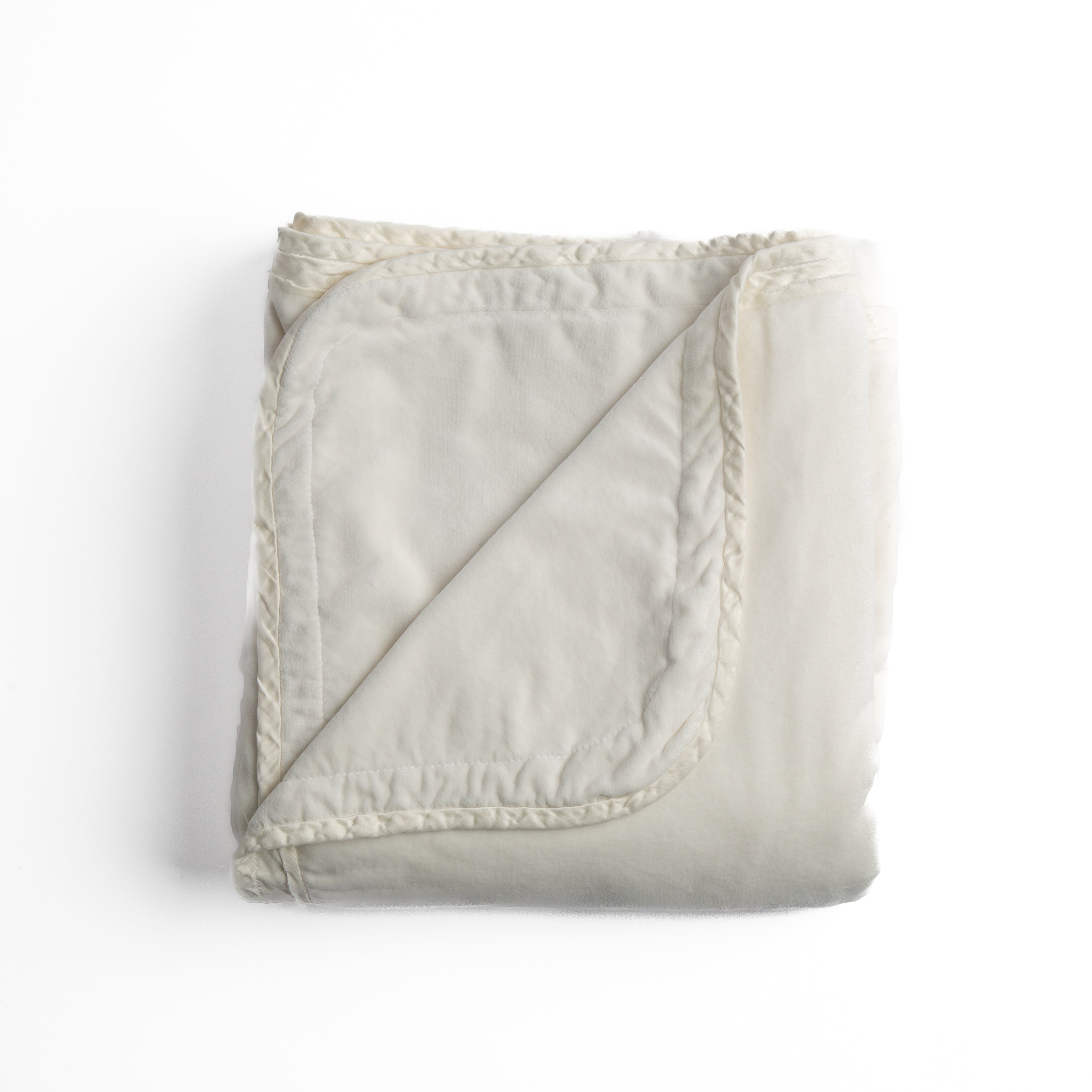 Winter White: overhead angle of the folded blanket with a corner pulled back to show the reverse and trim. 