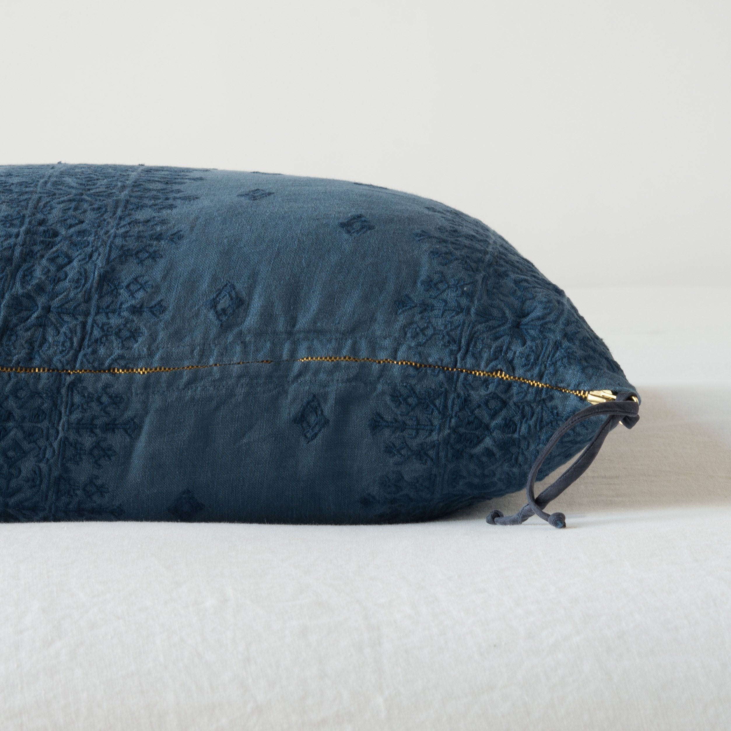 Midnight: Close-up of brass zipper and charmeuse pull details on throw pillow - side view.