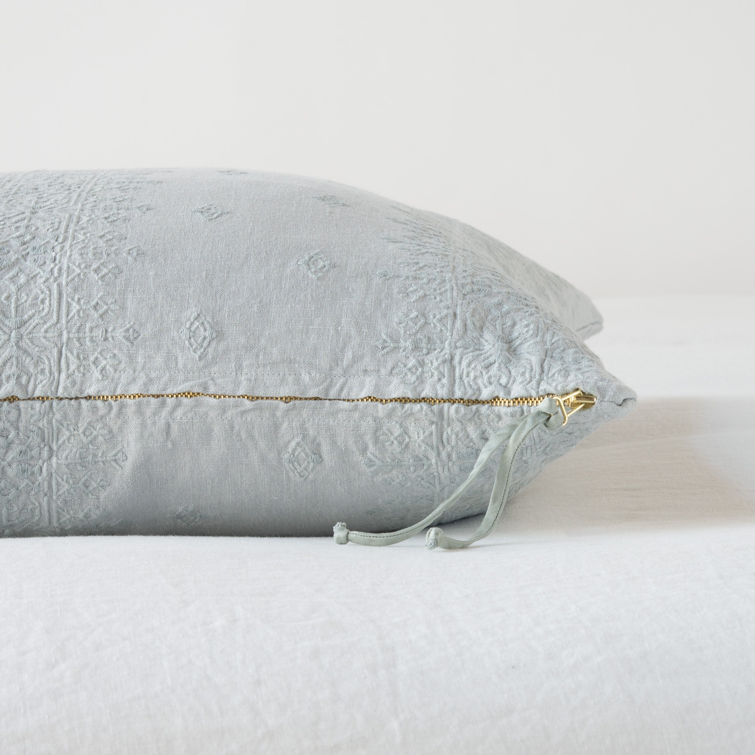 Mineral: Close-up of brass zipper and charmeuse pull details on throw pillow - side view.