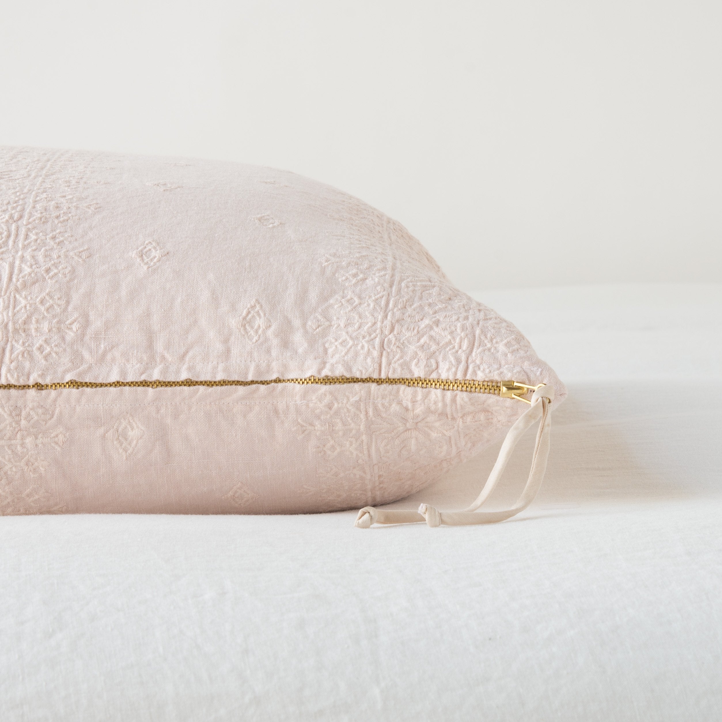 Pearl: Close-up of brass zipper and charmeuse pull details on throw pillow - side view.
