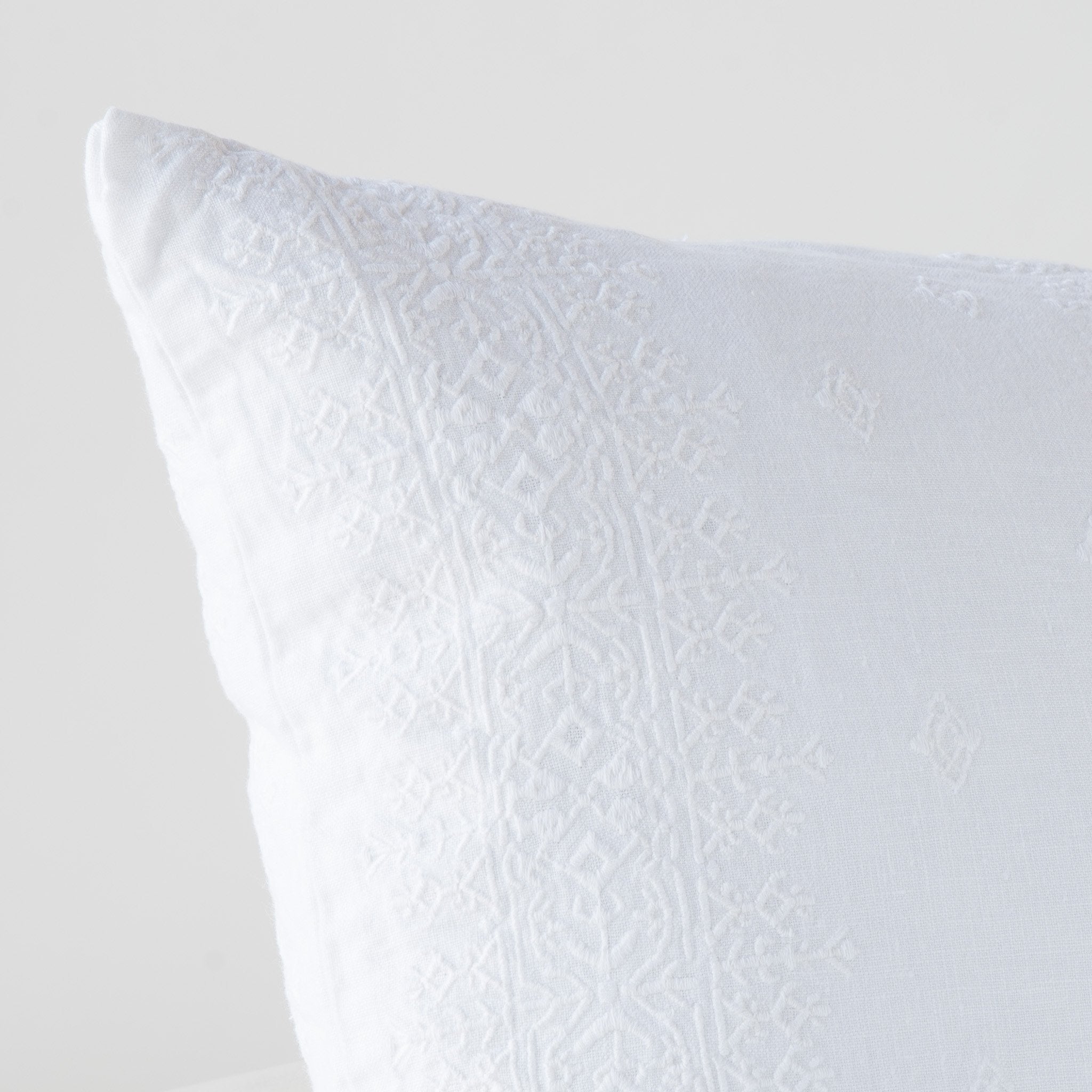 White: Close-up of pillow corner, showcasing the embroidery pattern detail.