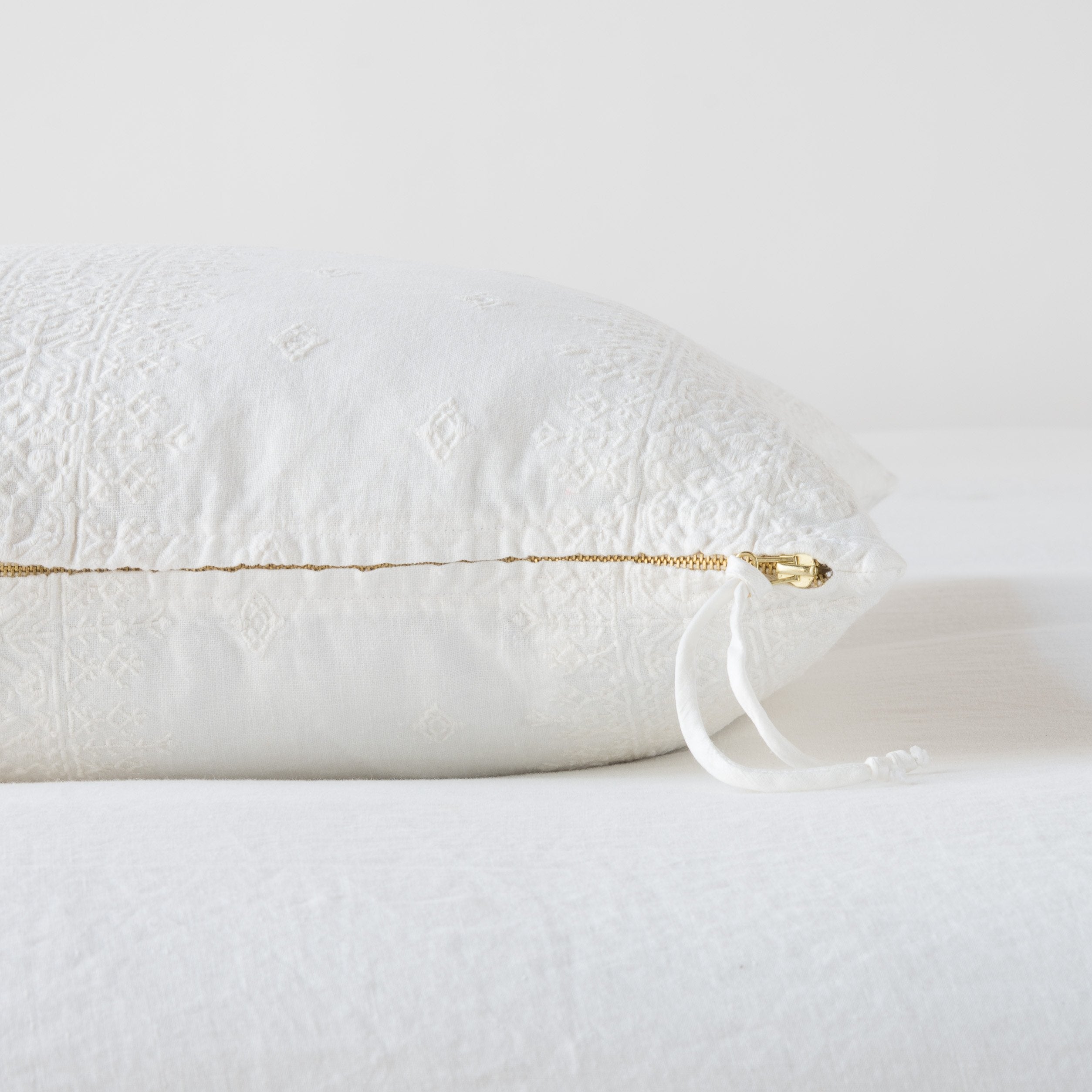 Winter White: Close-up of brass zipper and charmeuse pull details on throw pillow - side view.