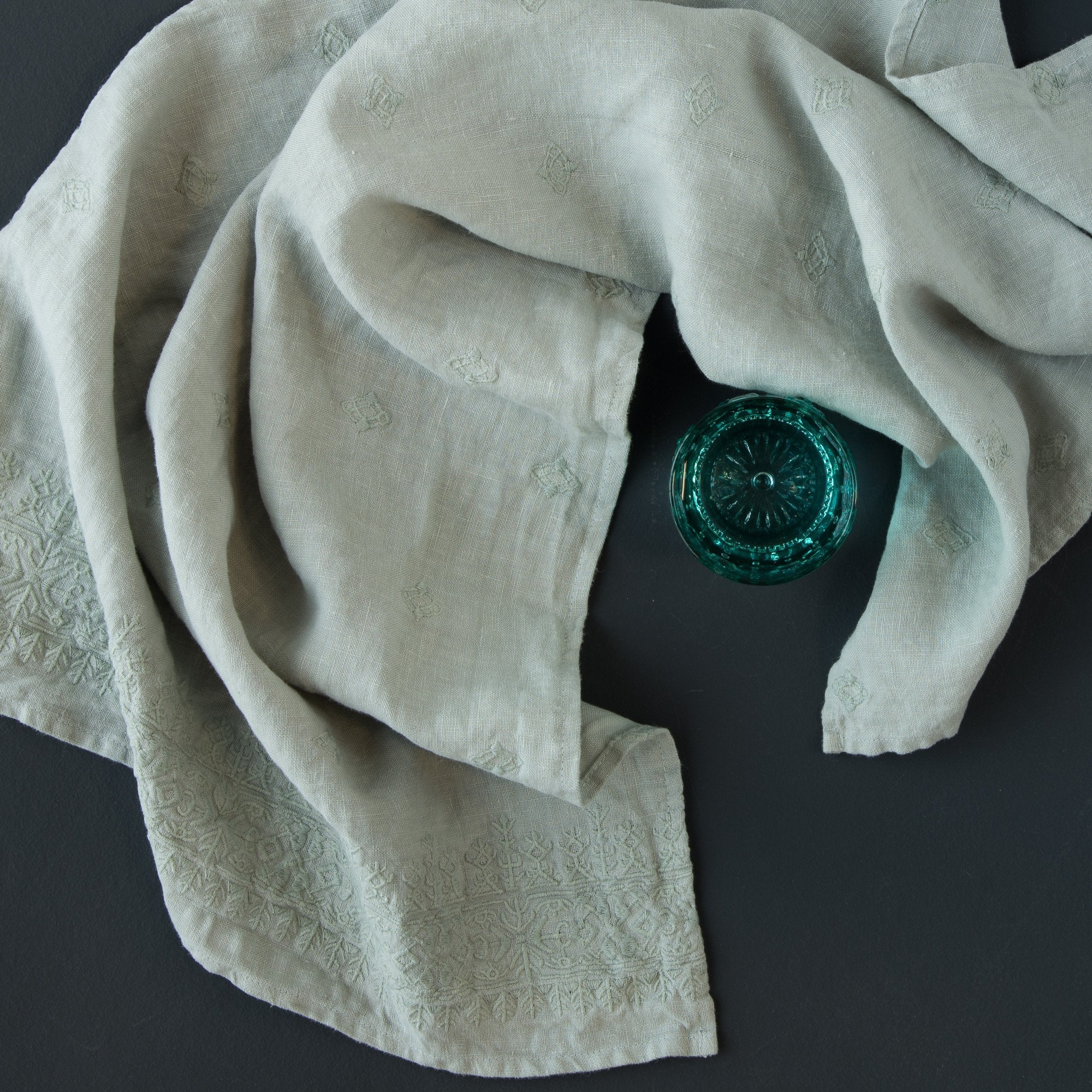 Eucalyptus: guest towel draped on a dark background around a dark green glass jar - overhead view.