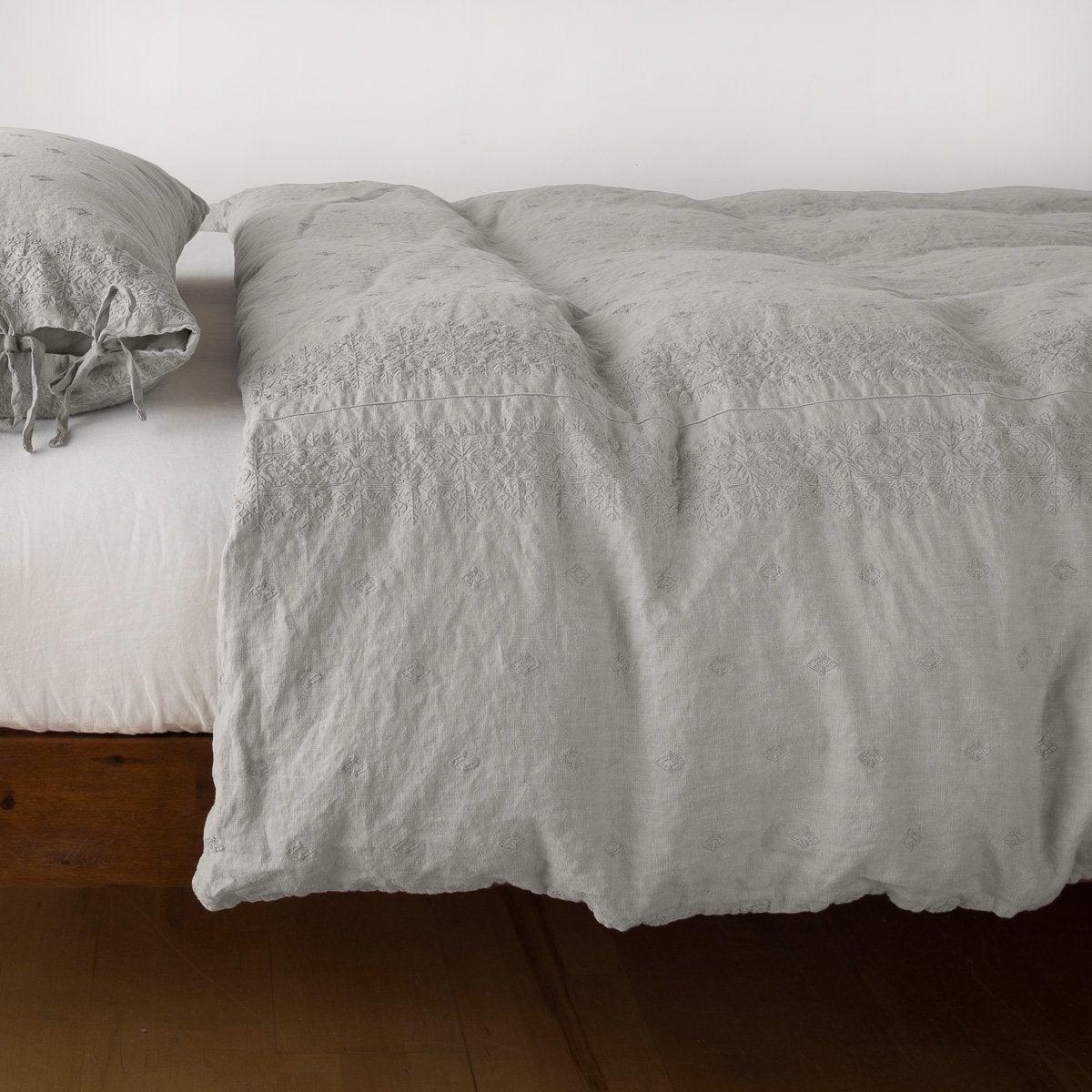 Fog: lightly rumpled duvet cover on a monochromatic bed against a white background - side view.