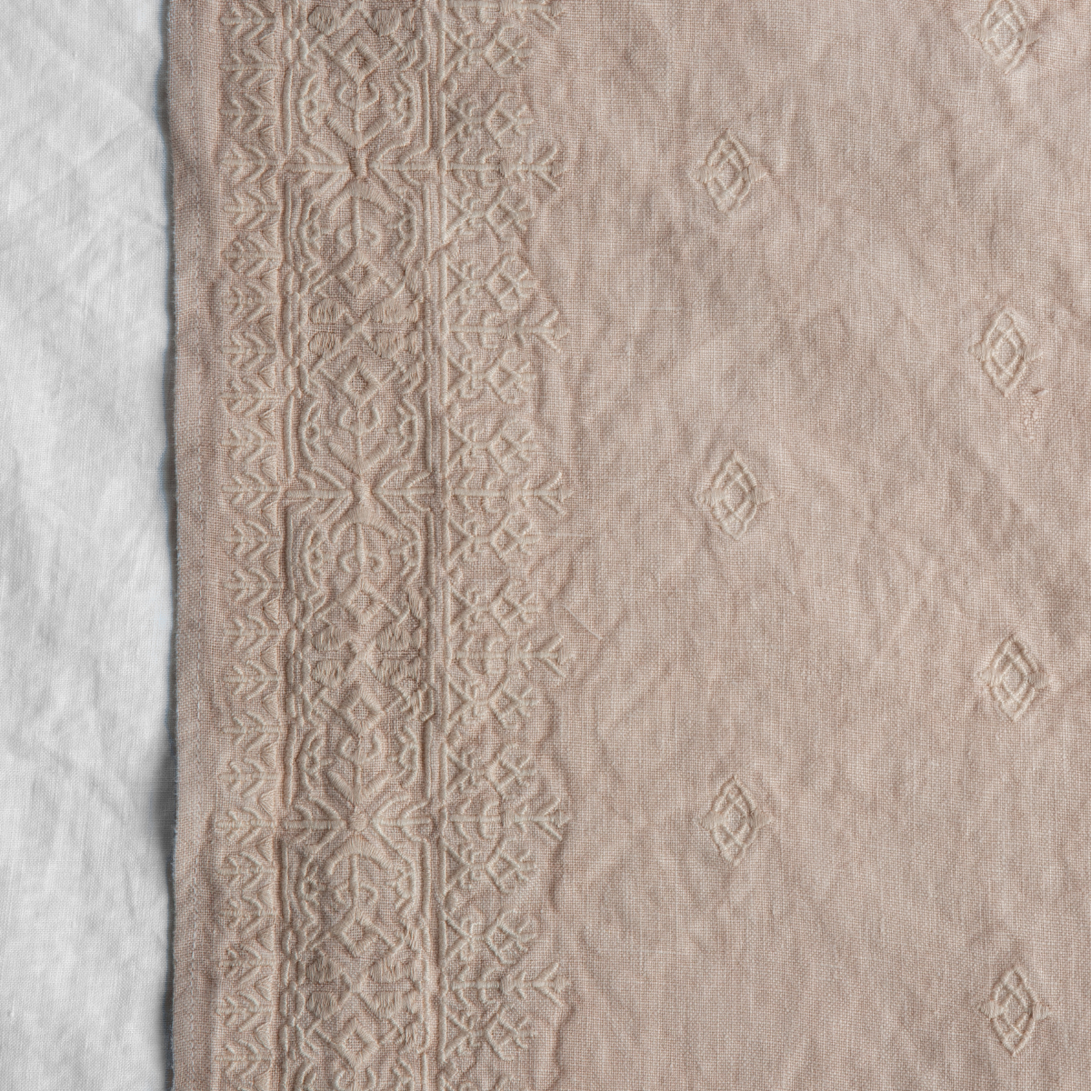 Pearl: A close up of Ines, midweight linen with cotton embroidery, in white.