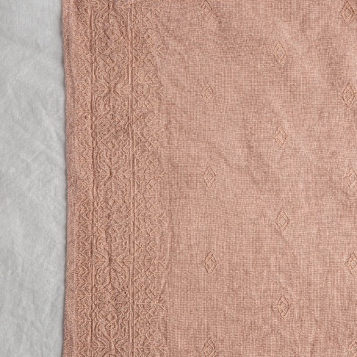 Rouge: A close up of Ines, midweight linen with cotton embroidery, in rouge, a mid-tone blush pink.