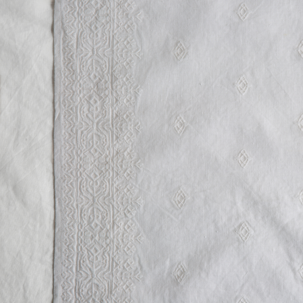 White: A close up of Ines, midweight linen with cotton embroidery, in white.