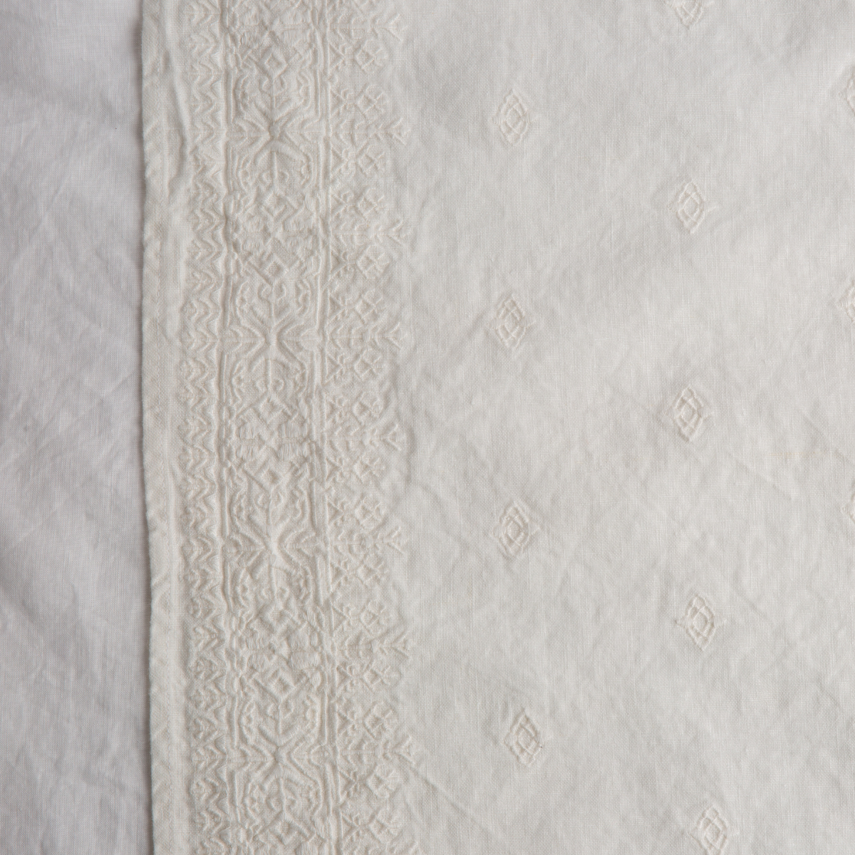 Winter White: A close up of Ines, midweight linen with cotton embroidery, in winter white, softer and warmer in tone than classic white.