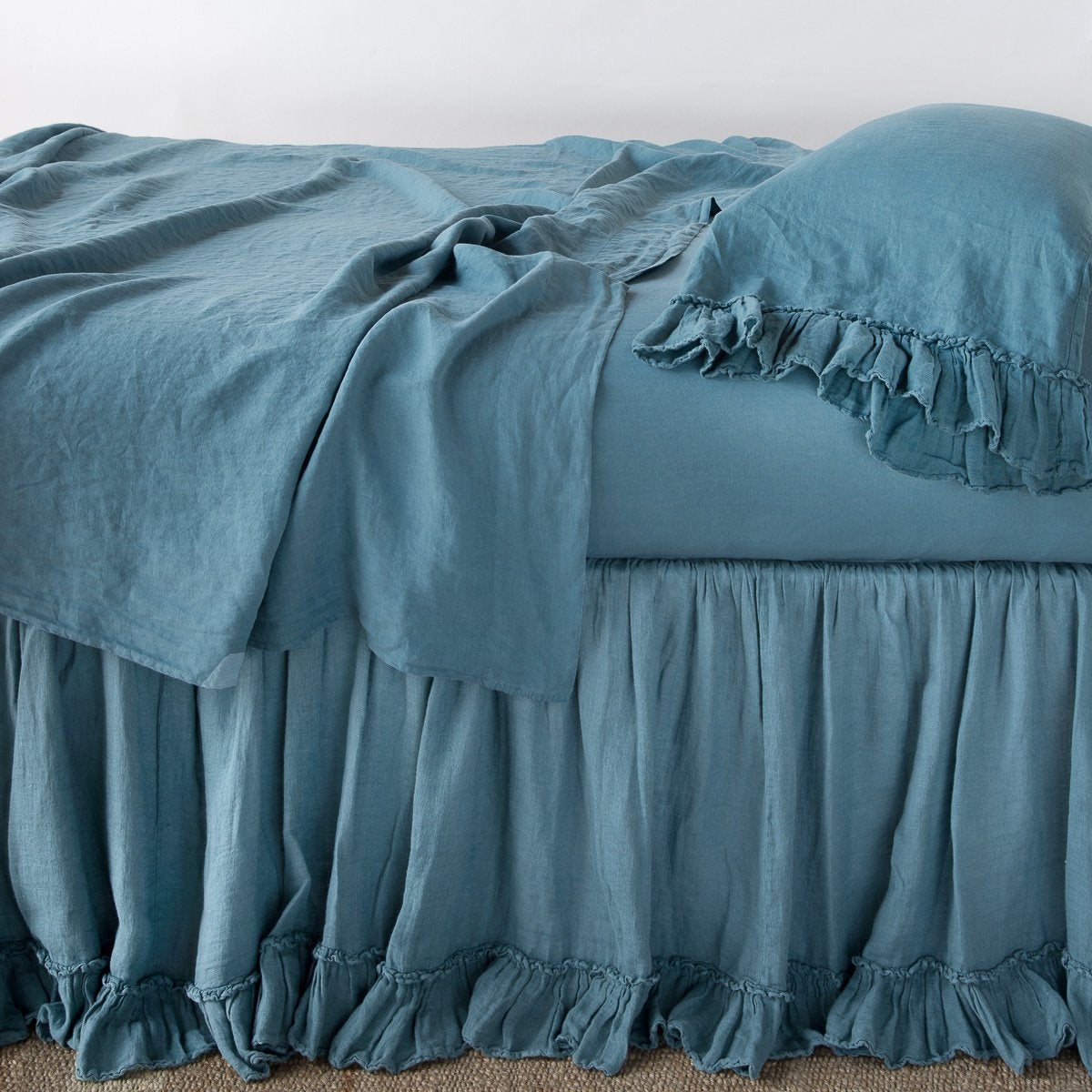 Cenote: bed skirt layered with monochromatic linen sheeting - side view.