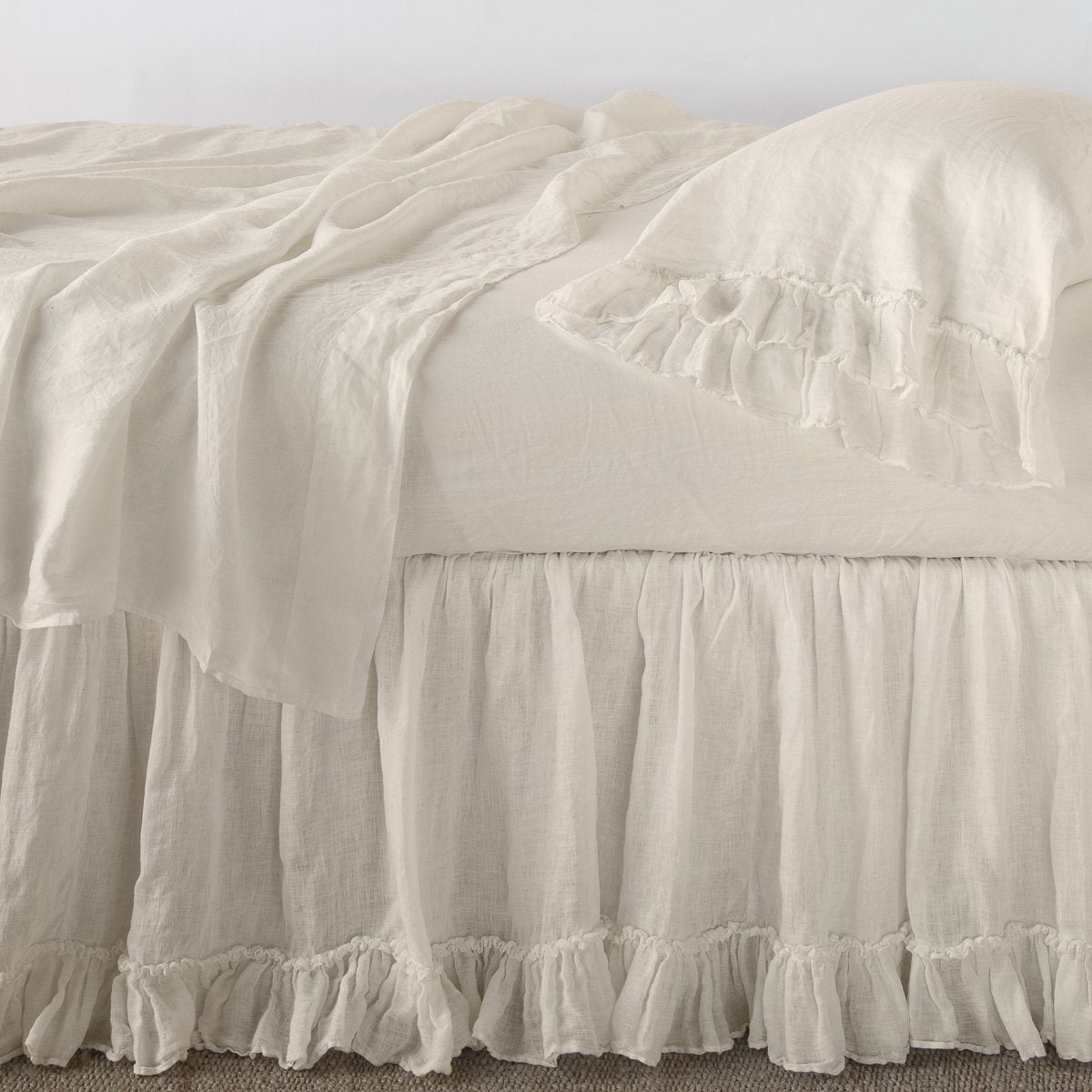 Parchment: bed skirt layered with monochromatic linen sheeting - side view.