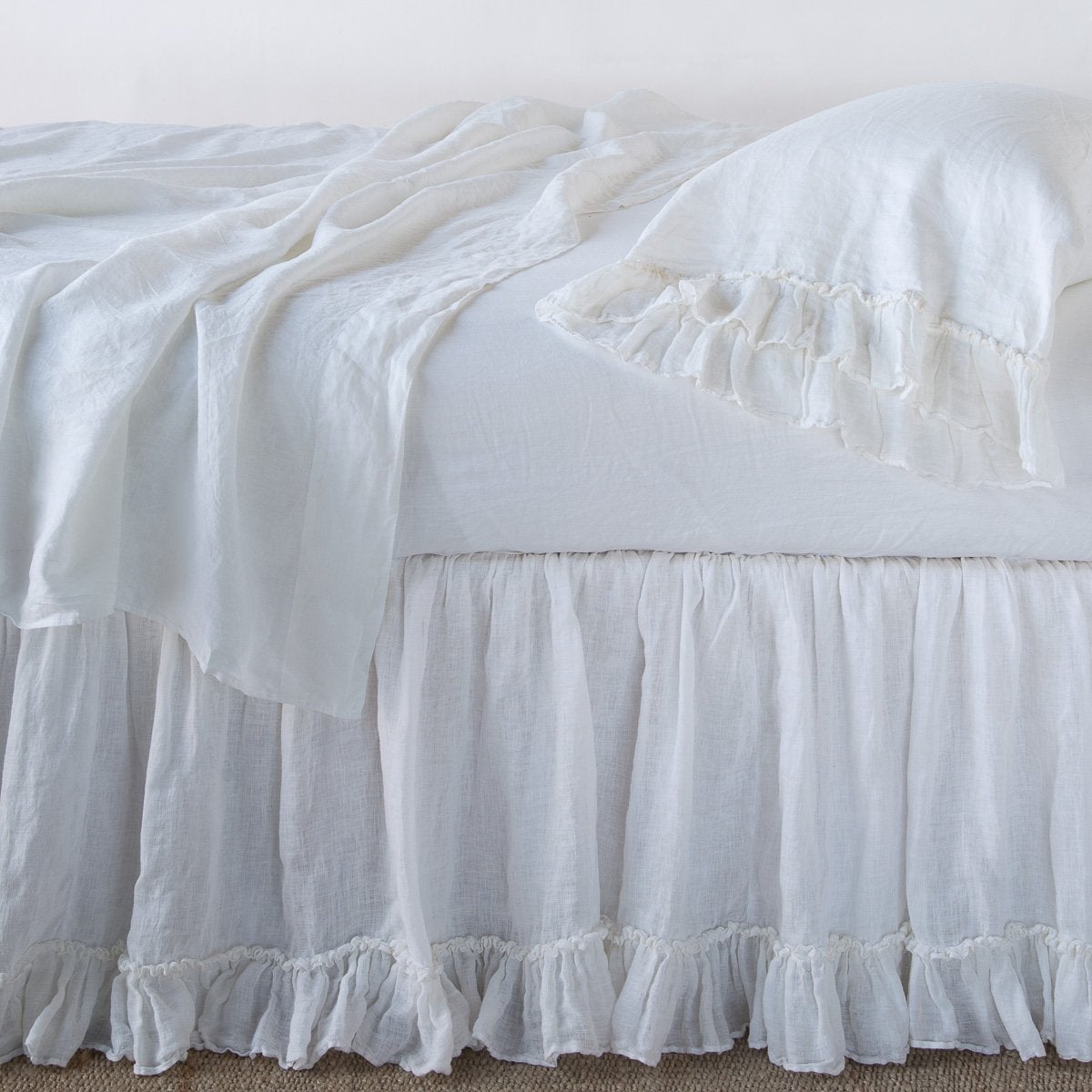 White: bed skirt layered with monochromatic linen sheeting - side view.