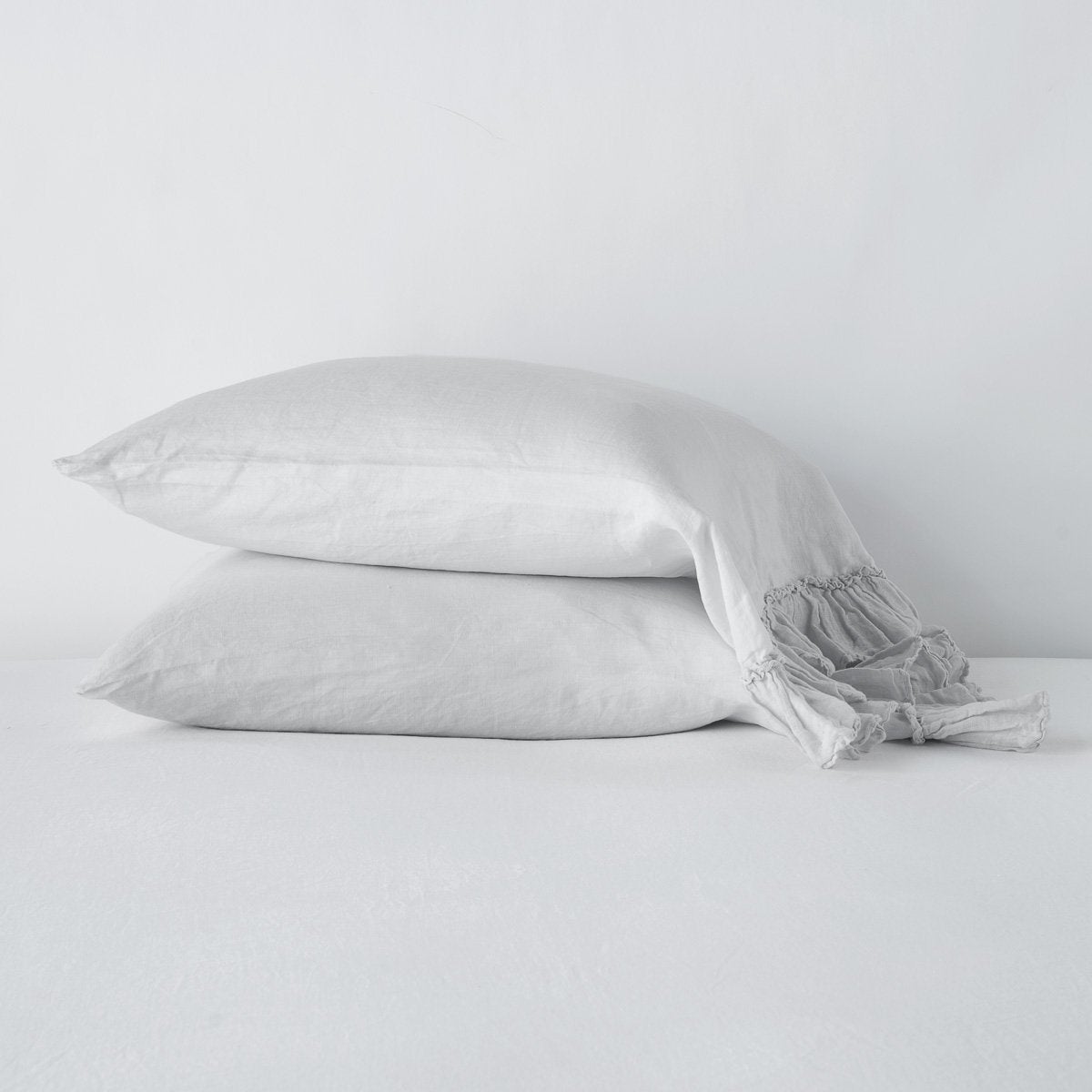 Sterling: Two sleeping pillows stacked at a slight angle against a plain background, showcasing ruffle trim detail - side view.