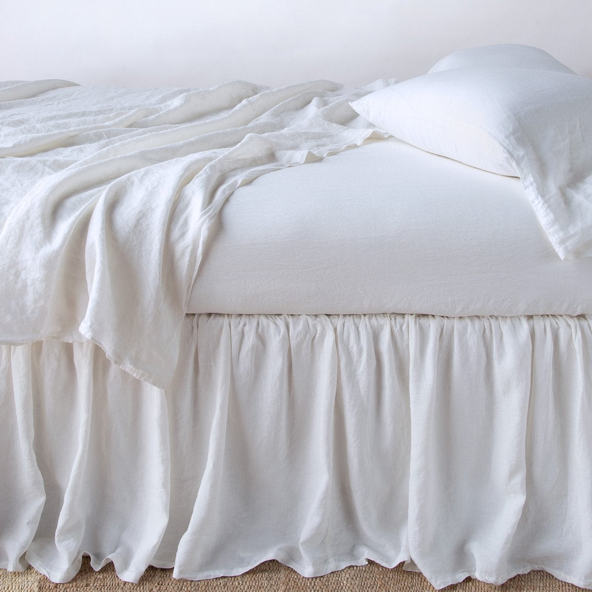 White: bed skirt with matching rumpled sheets and sleeping pillows - side view.