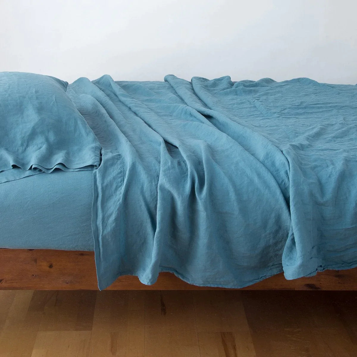 Cenote: fitted sheet with matching rumpled flat sheet and sleeping pillow - side view.