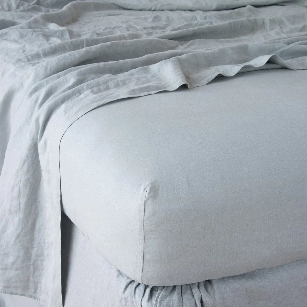 [allvariants]: Linen fitted sheet in mineral with matching rumpled flat sheet - shown from top corner.