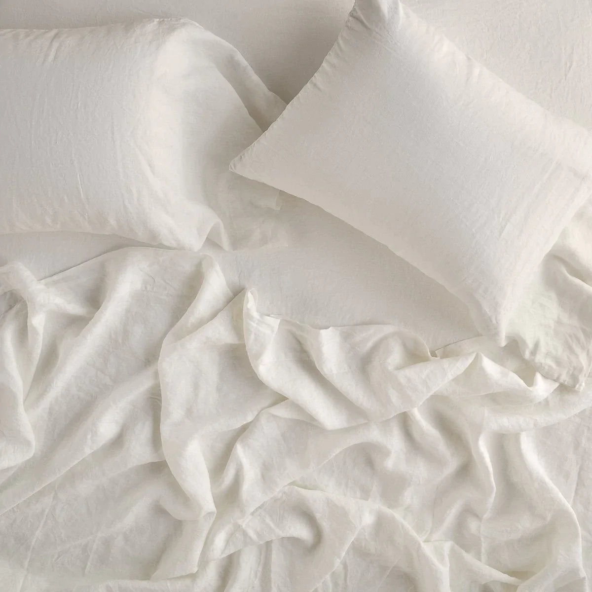Parchment: fitted sheet with matching rumpled flat sheet and sleeping pillows - overhead view.