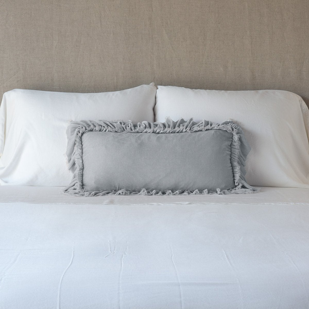 Sterling: pillow on a white bed - cropped end of bed view.