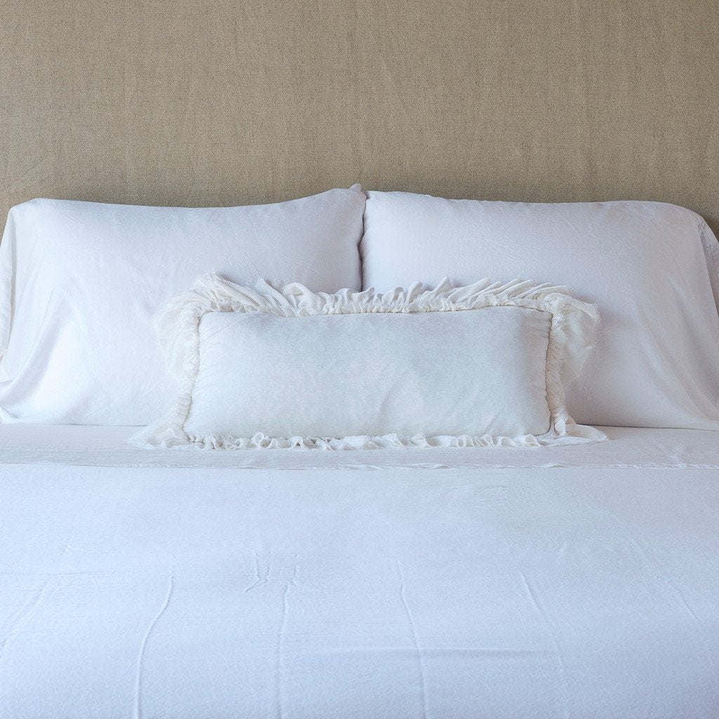 White: pillow on a white bed - cropped end of bed view.