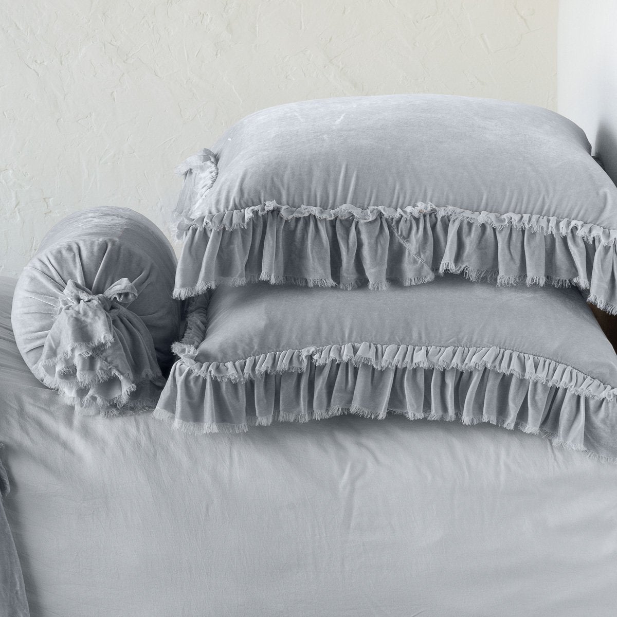Sterling: Two shams stacked flat next to matching bolster. Close-up side view highlights the ruffle trim.