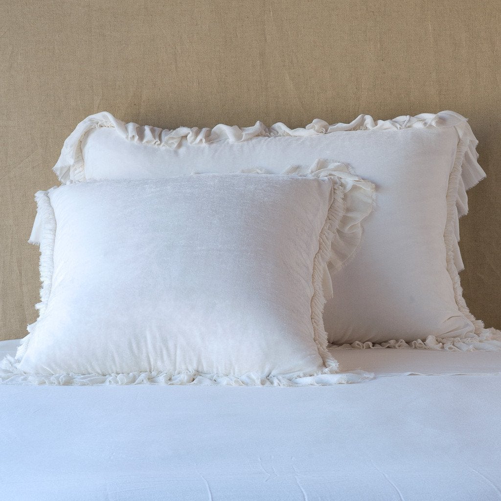 White: shams leaning upright on white sheets against a neutral headboard.
