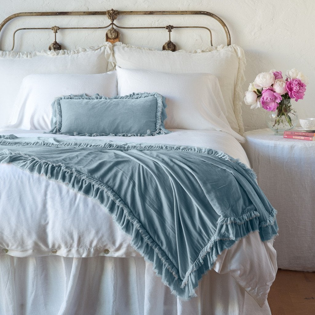 Cloud: throw blanket draped over the end of a white bed, shown with matching accent pillow - end of bed view.