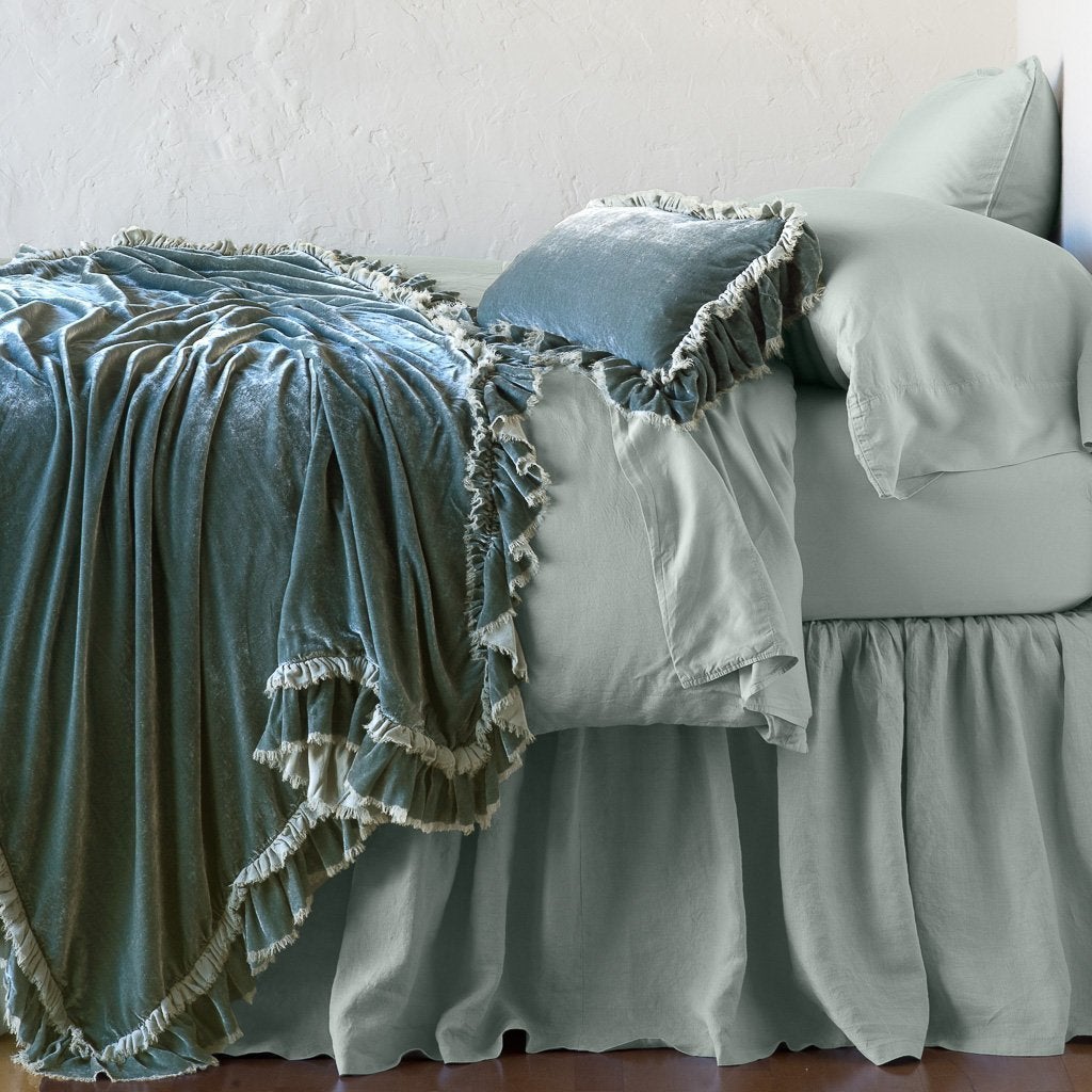Eucalyptus: throw blanket draped over a monochromatic bed, shown with matching throw pillow - side view.