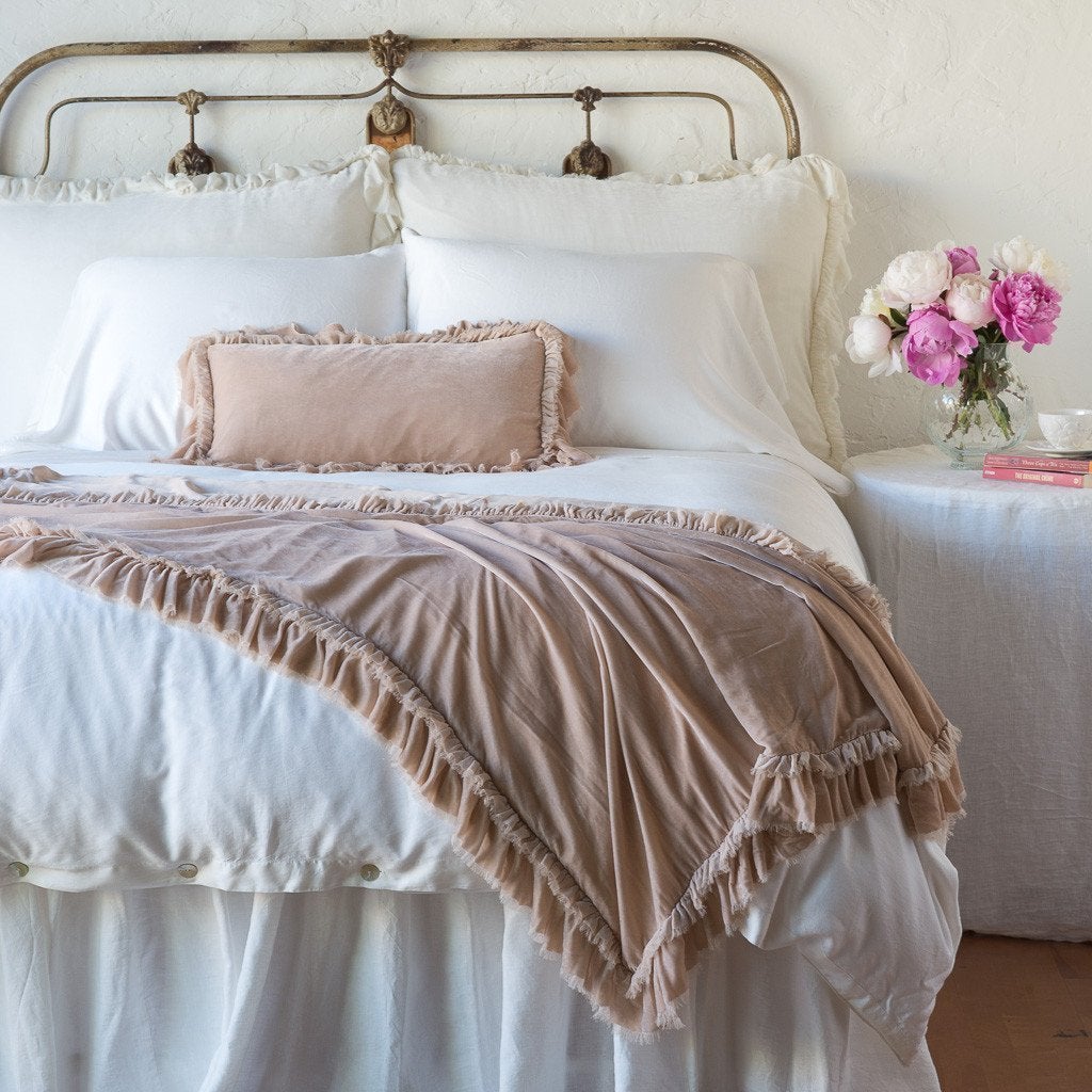 Pearl: throw blanket draped over the end of a white bed, shown with matching accent pillow - end of bed view.