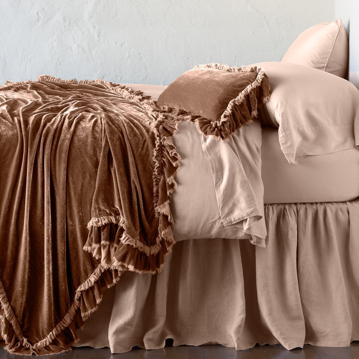 Rouge: throw blanket draped over a monochromatic bed, shown with matching throw pillow - side view.