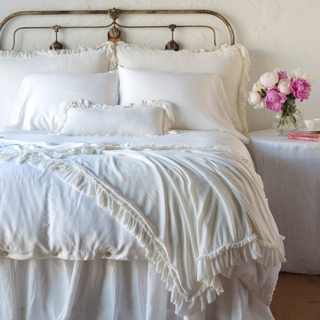 Winter White: throw blanket draped over the end of a white bed, shown with matching accent pillow - end of bed view.