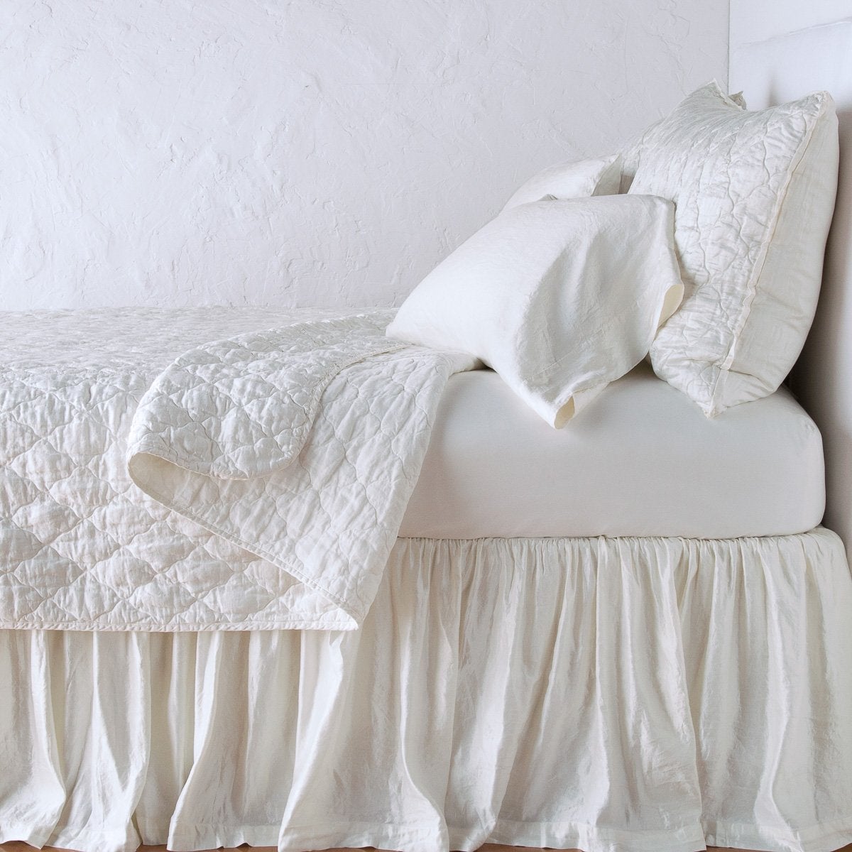 Winter White: coverlet neatly folded back to reveal linen reverse, on a monochromatic bed - side view.