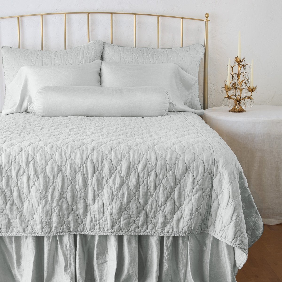 Cloud: shams on a shining, monochromatic bed with matching coverlet - end of bed view.