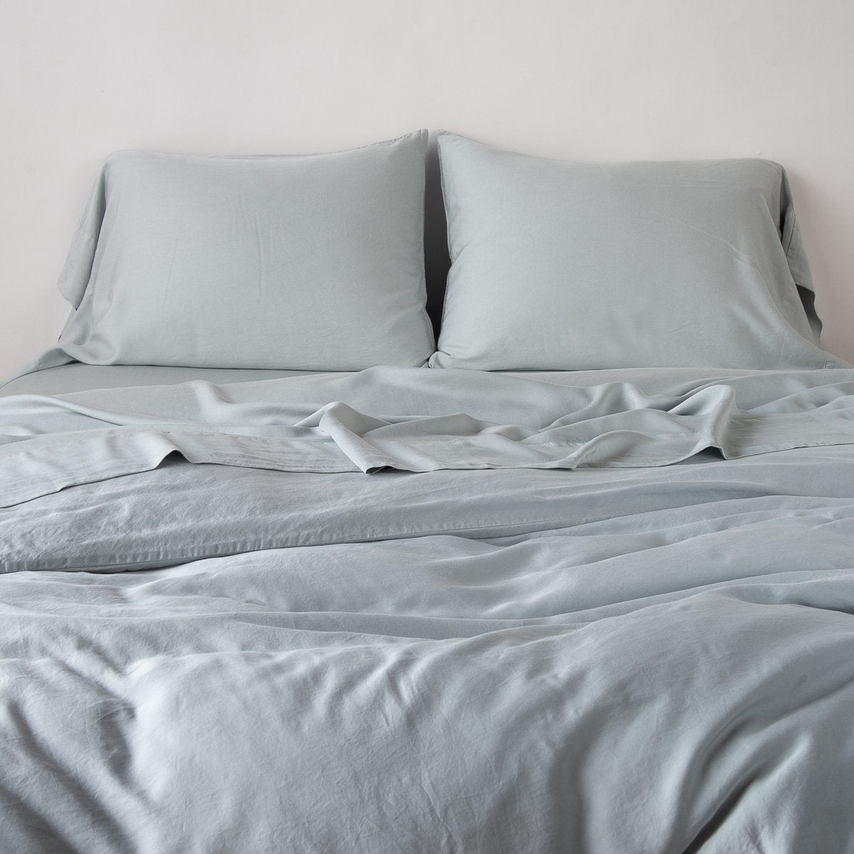 Mineral: duvet cover with matching sleeping pillows and sheeting against a white wall - end of bed view.