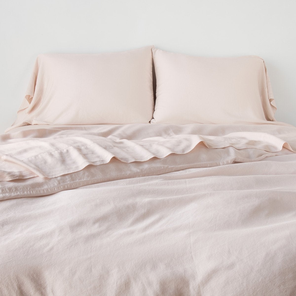 Pearl: duvet cover with matching sleeping pillows and sheeting against a white wall - end of bed view.