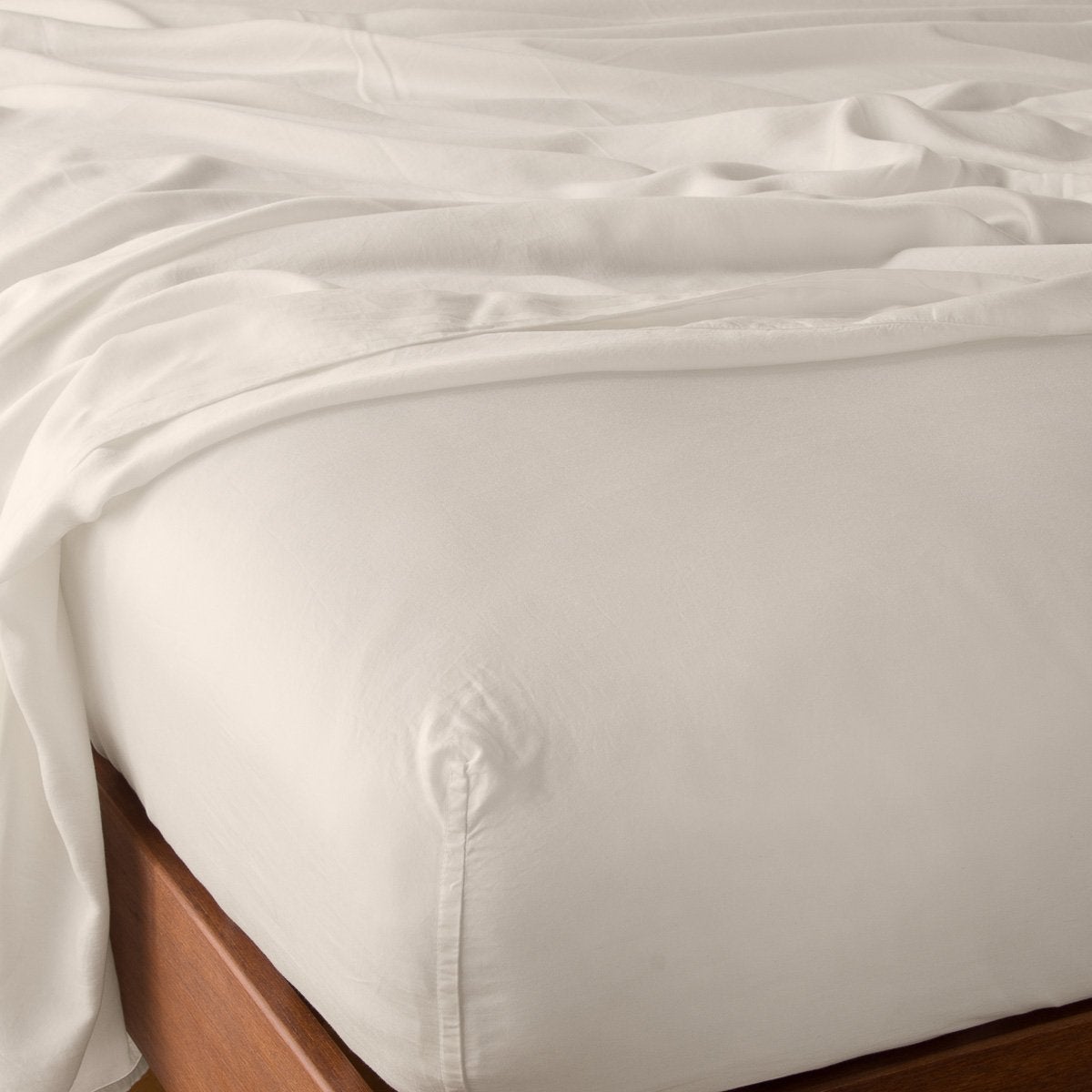 Parchment: fitted sheet with matching rumpled flat sheet - top corner view.