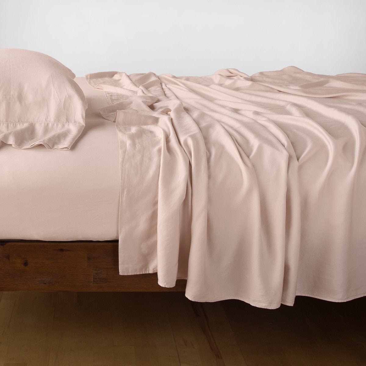 Rouge: Rumpled flat sheet with matching fitted sheet and sleeping pillow - side view.