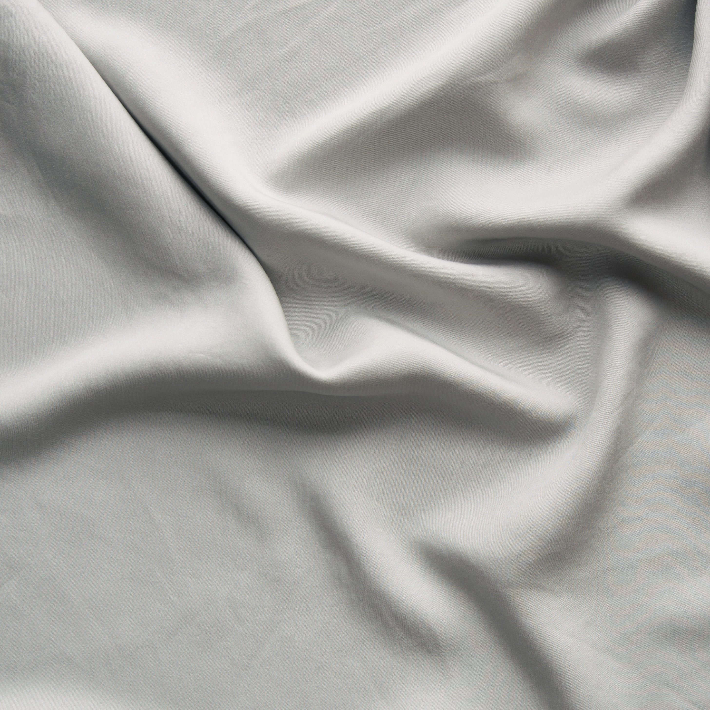 Fog: A close up of Tencel™ fabric in fog, a neutral-warm, soft mid-tone grey. 