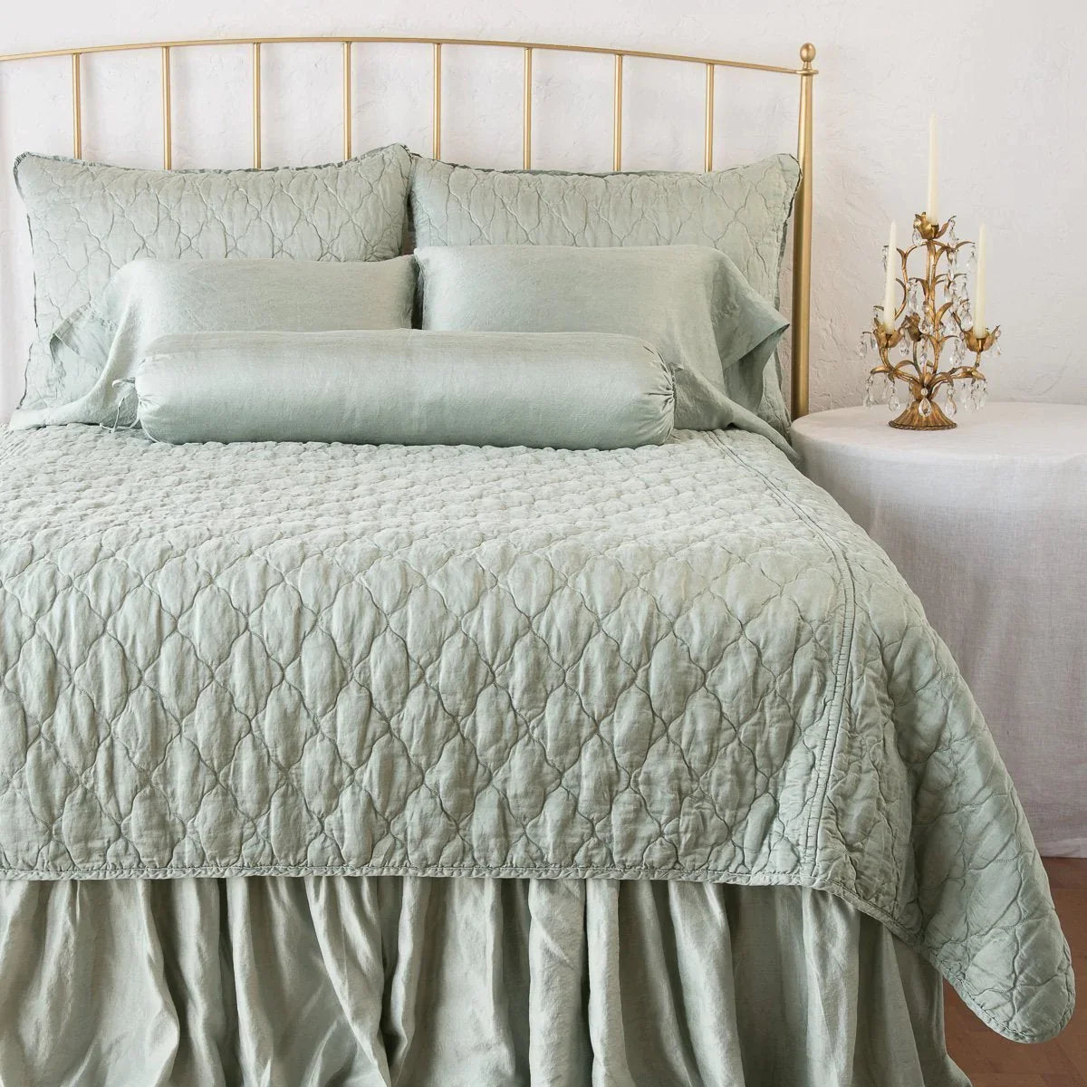 : Paloma bolster on a monochromatic, all-charmeuse bed - eucalyptus, end of bed view.