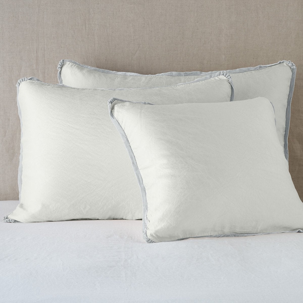 Sterling: shams leaning upright on white sheeting against a neutral headboard.