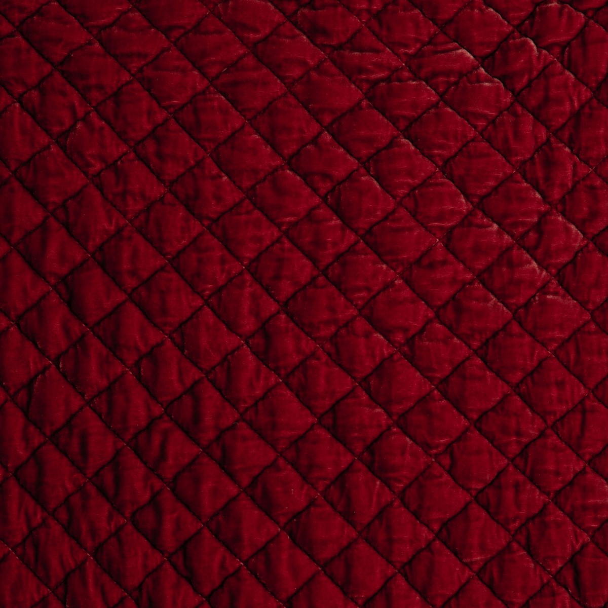 Poppy: Close-up of quilted silk velvet in poppy, a vibrant reddish pink.