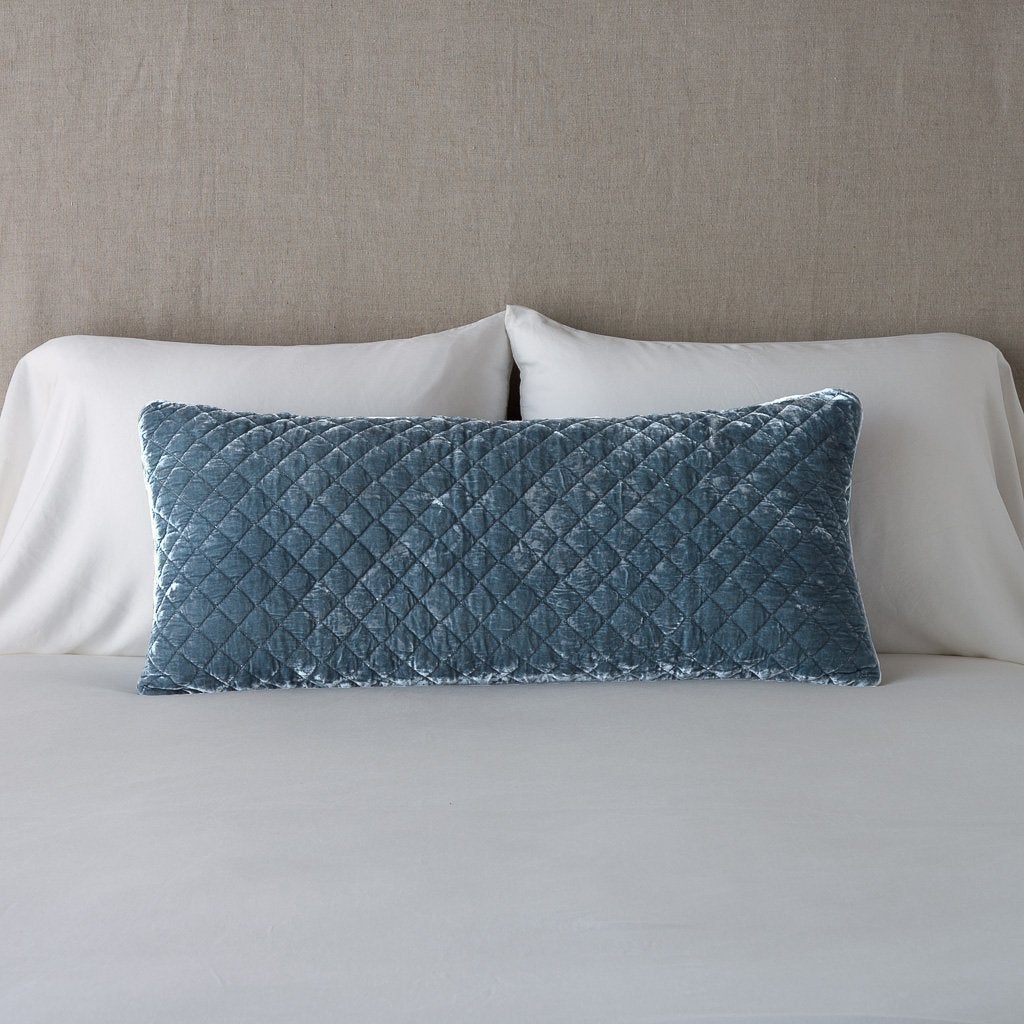 Mineral: Silk velvet 16x36 pillow leaning upright against white sleeping pillows and a neutral headboard.
