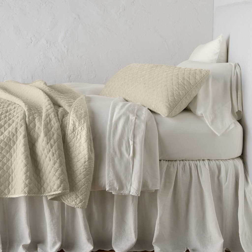 Parchment: 16x36 pillow with rumpled matching coverlet on monochromatic bed - side view.