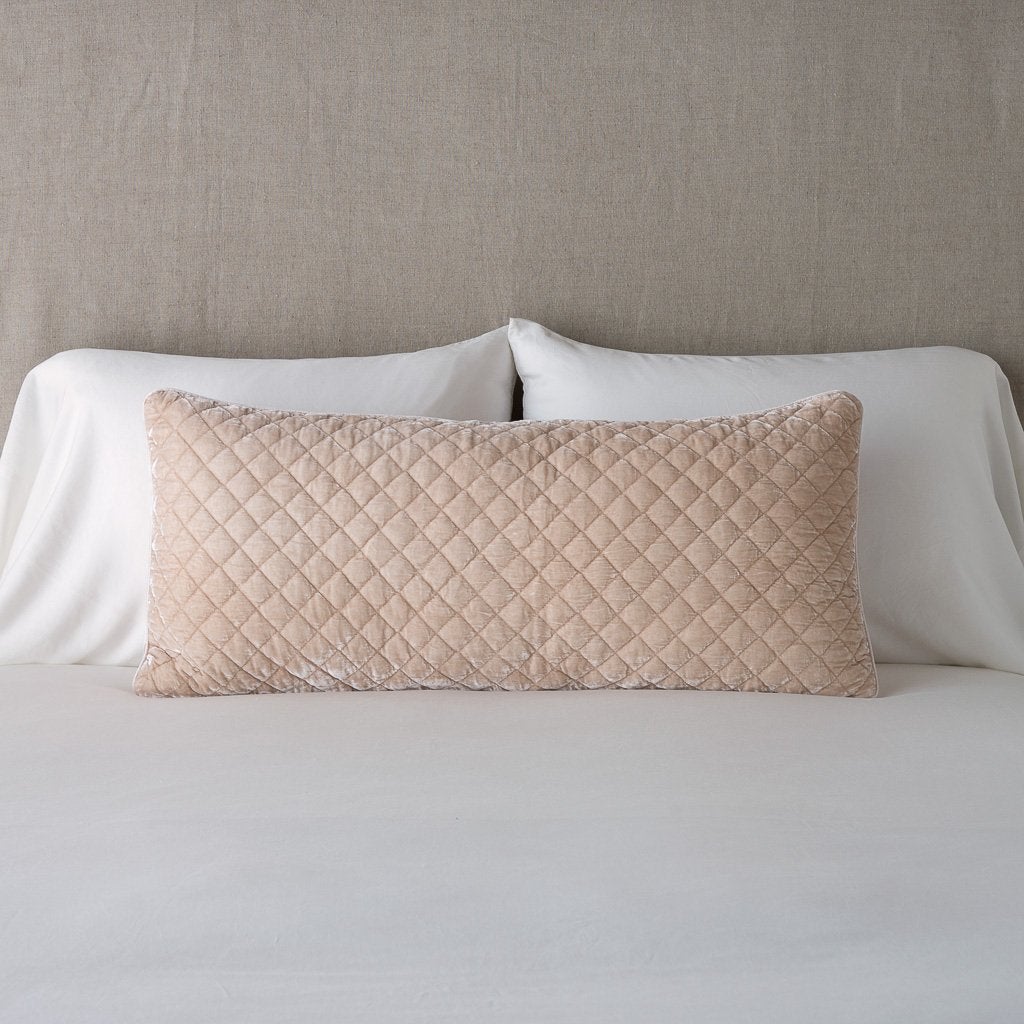Pearl: 16x36 pillow leaning upright against white sleeping pillows and a neutral headboard.