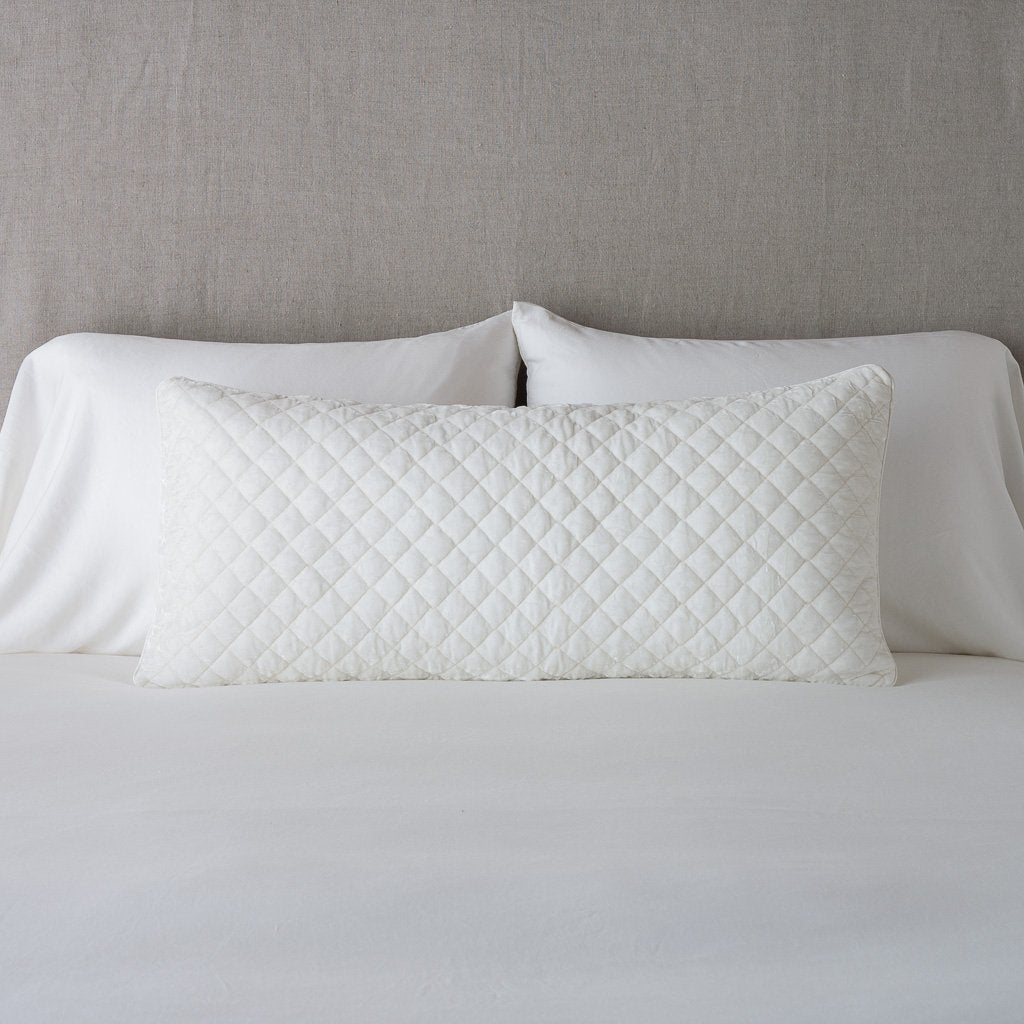 Winter White: 16x36 pillow leaning upright against white sleeping pillows and a neutral headboard.