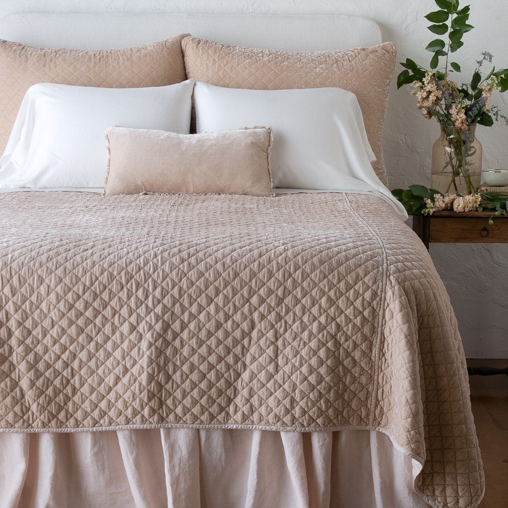 Pearl: shams with matching coverlet on a neatly-made, bed with white sheeting - end of bed view.