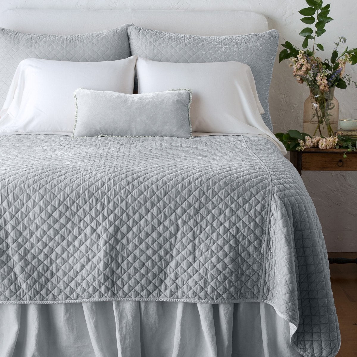 Sterling: shams with matching coverlet on a neatly-made, bed with white sheeting - end of bed view.